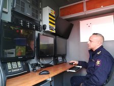 Funkcjonariusz Straży Ochrony kolei prezentuje wnętrze Mobilnego Centrum Monitoringu, czyli specjalistycznego samochodu służbowego wyposażonego w system kamer dziennych i nocnych.